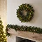 wider image of cranberry and pine garland on a mantlepiece, with wreath hanging above