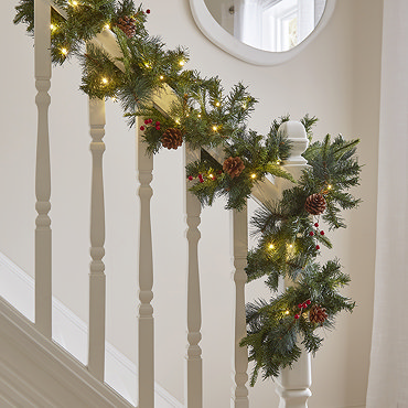 close up image of cranberry and pine garland draped on a light oak mantlepiece