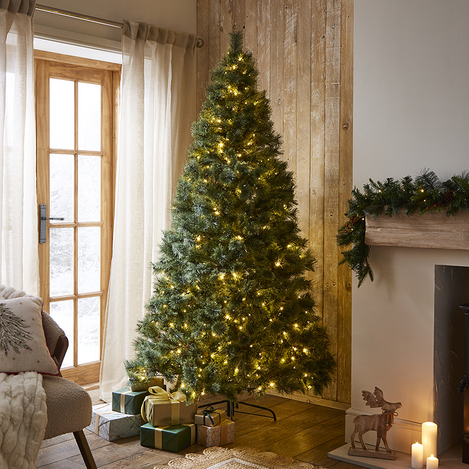 pre-lit lush pine tree with warm white LEDs stood in the middle of cosy living room