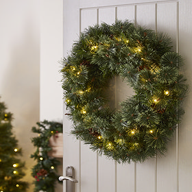 pre-lit pine wreath hung on the back of a white wooden living room door