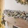 close up image of snowy garland with warm white LEDs draped across a light oak mantlepiece