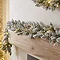 close up image of snowy garland with warm white LEDs draped across a light oak mantlepiece