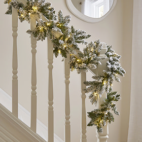 snowy green garland with warm white LEDs wrapped around a bannister