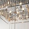 image taken from below looking upwards into large rectangular chrome ceiling light with bevelled glass sides and six candle-capped bulbs