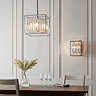 image of cubed chrome ceiling light hanging over a dining table with matching wall light on wall behind and to the right side of it