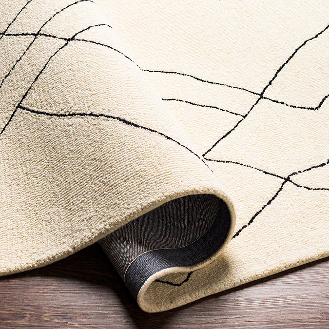 image of cream wool rug with black lines folded slightly to show its thickness