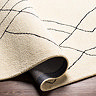 image of cream wool rug with black lines folded slightly to show its thickness
