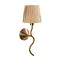 image cut out on white background of wriggle shaped wall light in brushed brass with raffia shade