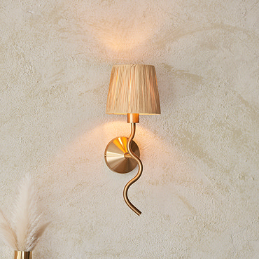 side on image of brushed brass wriggle light with raffia shade on cream wall