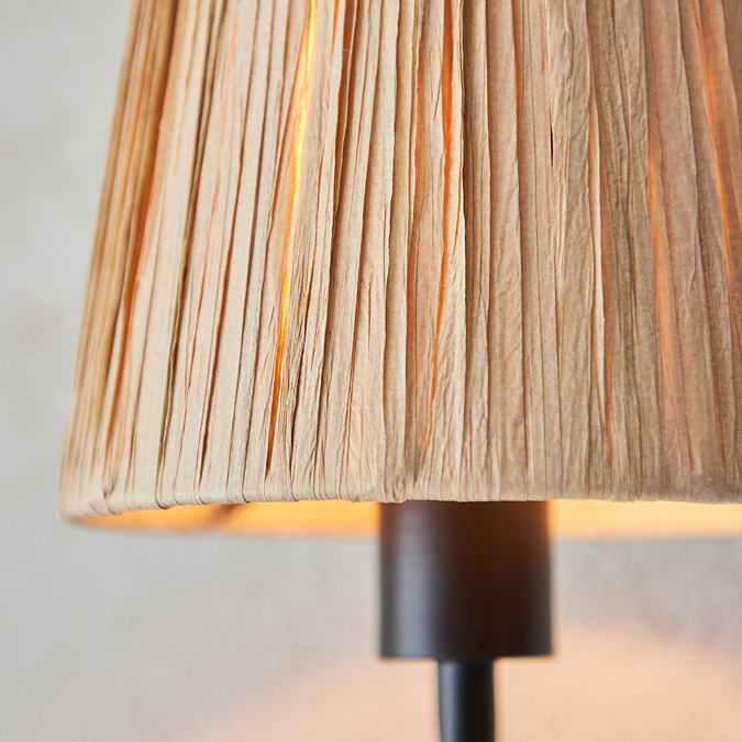close up on raffia shade of matt black wriggle wall light, showing where shade meets black steel body