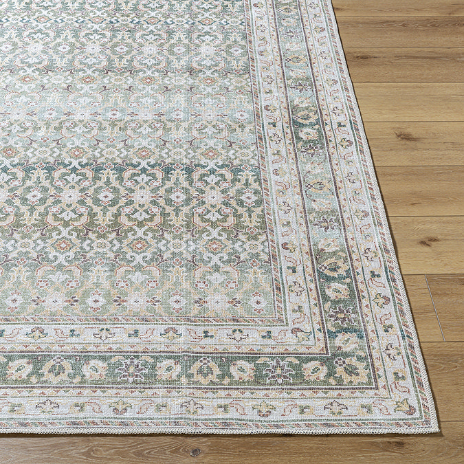 image of corner of olive green boho rug on light wooden flooring