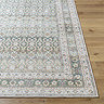 image of corner of olive green boho rug on light wooden flooring