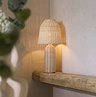 image of natural coloured rattan lamp in corner of room resting on a wooden side panel