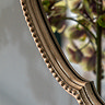 close up image of left side of champagne gold wall mounted mirror, focus on beaded edge detail