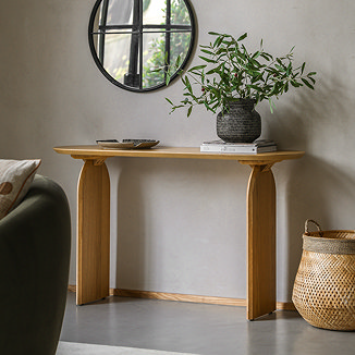 light oak console table at the back of a living room with a bowl and plant on