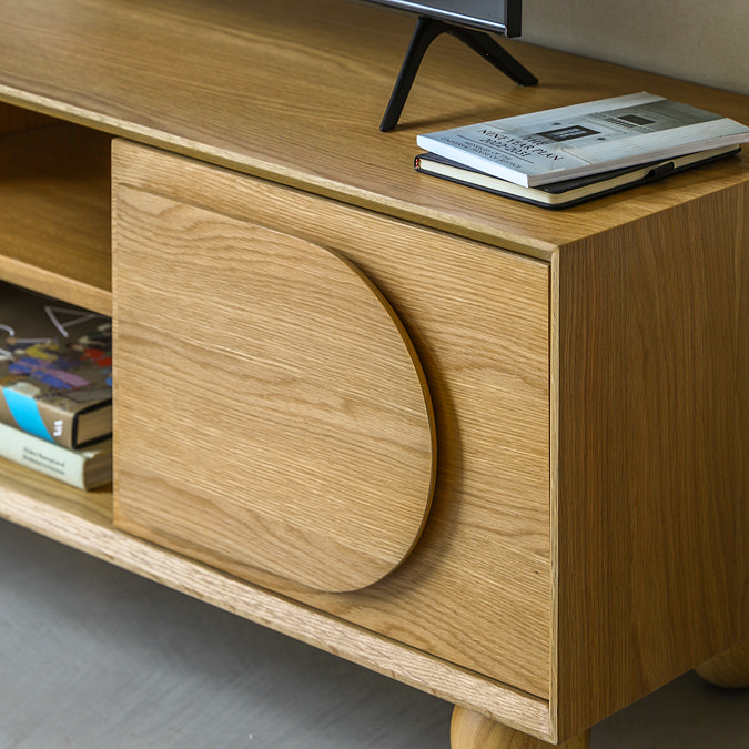 close up on right side cupboard of media unit in light oak veneer, with curved shaping