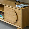 close up on right side cupboard of media unit in light oak veneer, with curved shaping