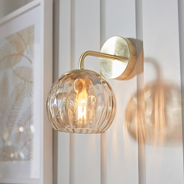 angled image of dimpled glass champagne coloured wall light against cream wall