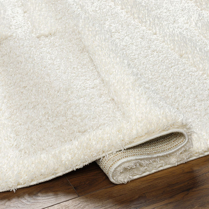 close up on super soft cream rug folded over at edge to suggest thickness