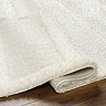 close up on super soft cream rug folded over at edge to suggest thickness