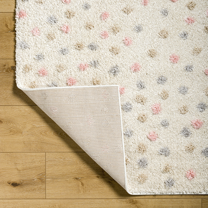close up image on corner fold of cream and multi coloured dotted rug