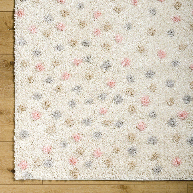 close up on corner of cream rug dotted with multi coloured spots