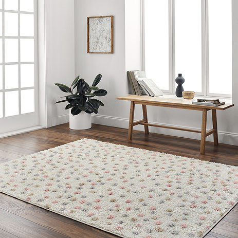 image of cream super soft rug patterned with multi coloured dots, on dark wooden flooring of home office in front of low bench and window