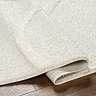 close up image of folded edge of cream super soft rug