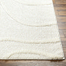 close up image of corner of super soft cream rug with raised abstract lines, on wooden flooring