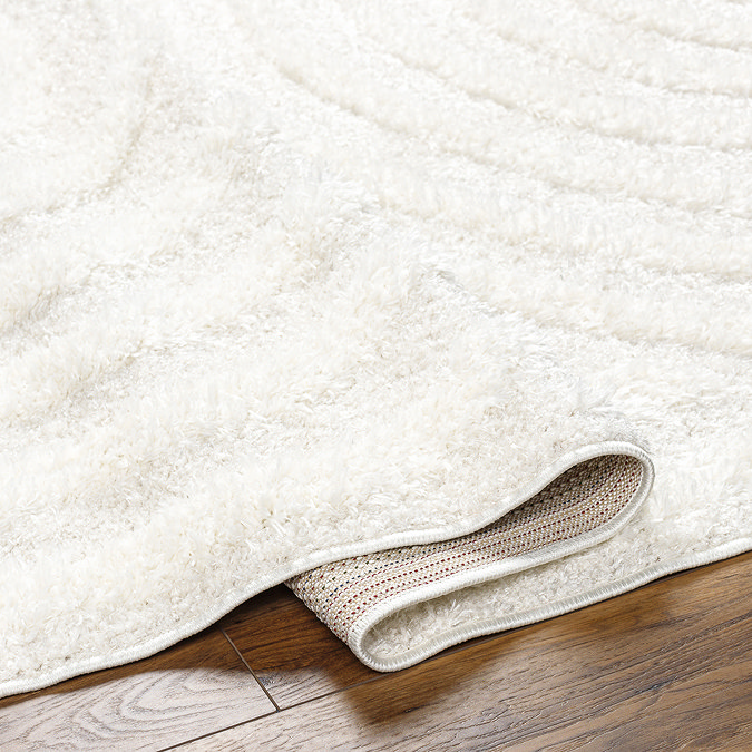 close up image of folded edge of soft cream rug to suggest its height/thinness