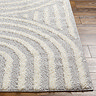 close up on corner of soft grey rug with arch line pattern, on light wood flooring
