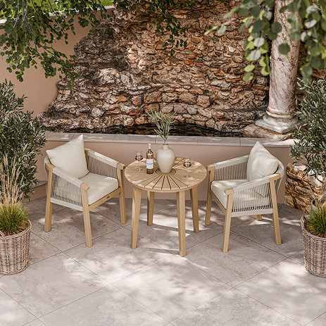 image taken from slightly above of acacia wood bistro table with rope weave dining chairs, on stone patio