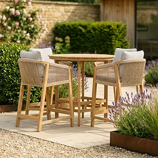 image of round acacia wood bar table with tall rope weave bar chairs around it, on stone square of a garden