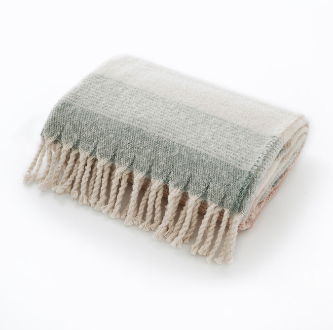 pale pink and green throw folded up with tassels, cut out on white background