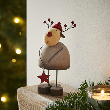trio of rustic wooden figures stood on the mantlepiece, a tall santa with smaller santa and smaller reindeer on either side. 