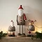 tall rustic santa stood on a mantlepiece, with a small santa and small reindeer on either side. 