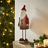tall rustic santa stood on an oak mantlepiece, surrounded with candles and a small garland. 