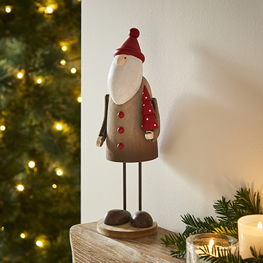 tall rustic santa stood on a mantlepiece, with a small santa and small reindeer on either side. 