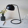 image taken from above of matt black table lamp with circular base on white marble surface