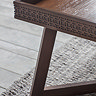 close up image on corner of brown coffee table with frieze round the edge
