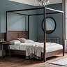 image of four poster brown wooden bed against duck egg blue wall