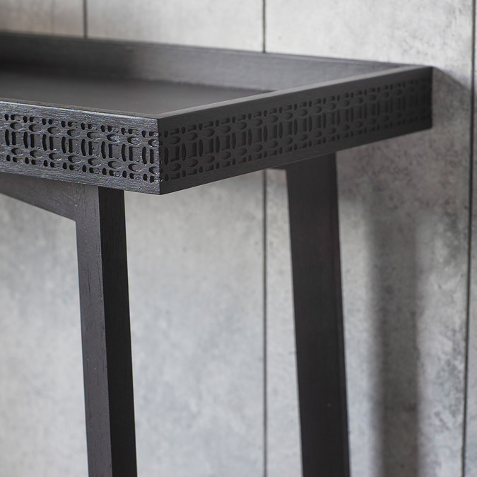 close up image of side of black console table with frieze pattern around the edge