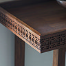 super close up image of corner of warm brown console table with frieze pattern