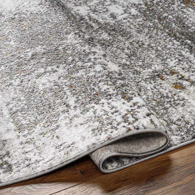 close up image of folded over edge of charcoal grey abstract rug