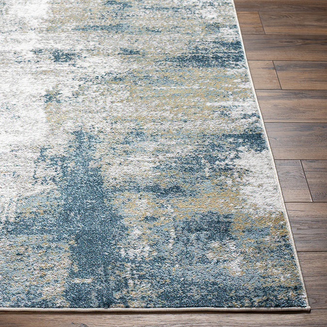 close up image on teal corner of abstract rug on dark wooden flooring