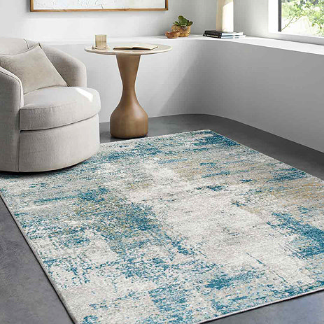 image of abstract teal and ivory rug in a small front room with modern armchair on top of it in the left corner, in front of a window