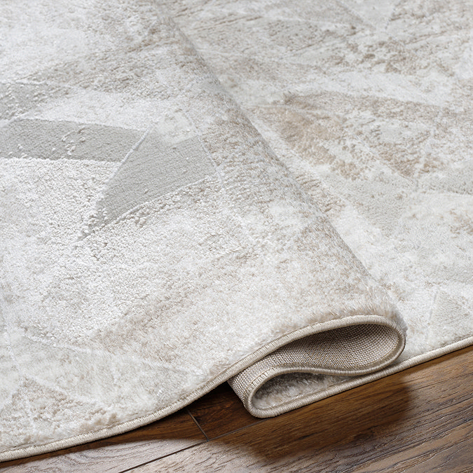 close up image of ivory and tan geometric block rug folded over to show thickness