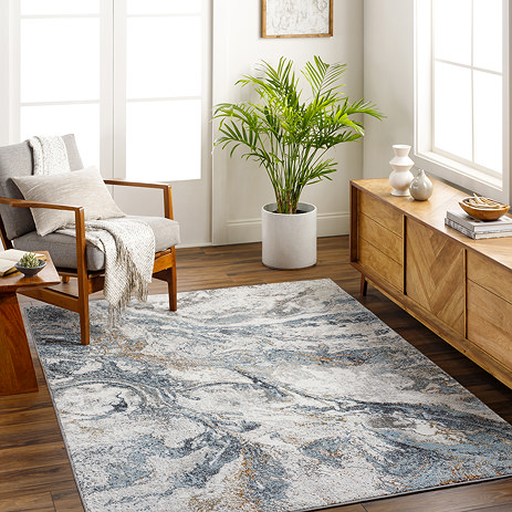 image or marbled pattern rectangular rug in blue and grey shades, on dark wooden flooring of modern apartment under an armchair