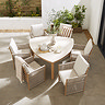 image taken from above looking down on triangular shaped table with chunky cream chairs, on stone garden patio surrounded by fences and foliage