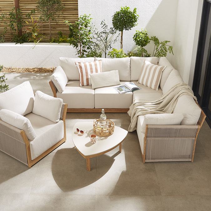 image angled slightly from above of luxury garden lounge set with deep cushions and cream stone topped coffee table